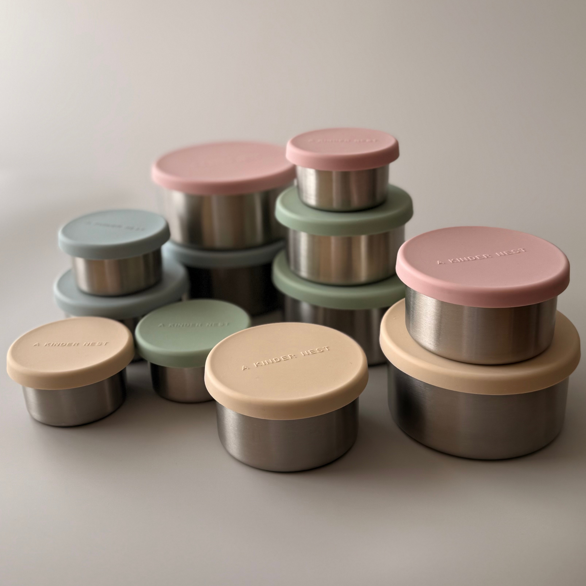 A Kinder Nest set of 3 nesting stainless steel food storage containers with leakproof LFGB silicone lids for plastic-free snacks.