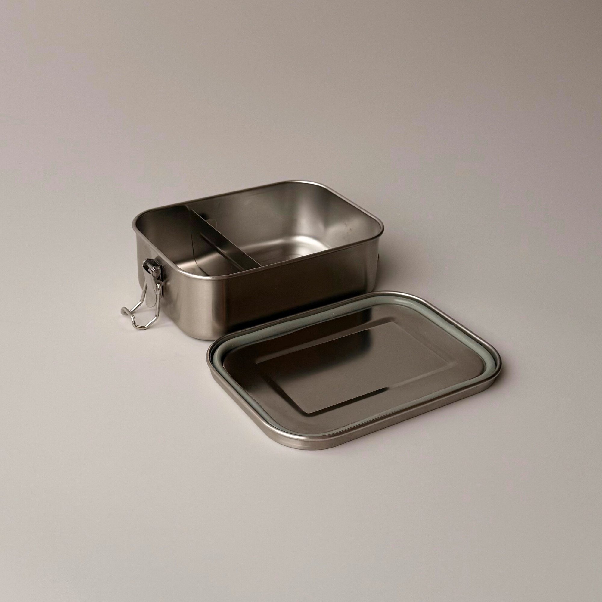 Interior view of a metal lunch box showing the adjustable and removable divider for organized meal prep and food separation.
