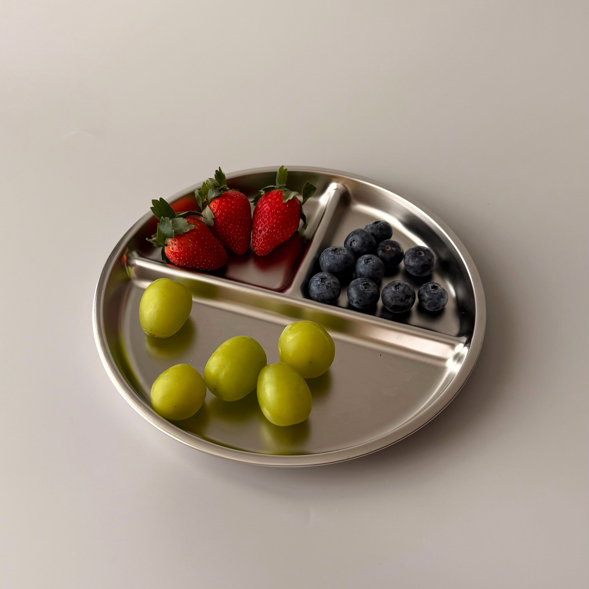 A Kinder Nest 3-section stainless steel divided plate for kids, featuring a plastic-free and shatter-proof design.