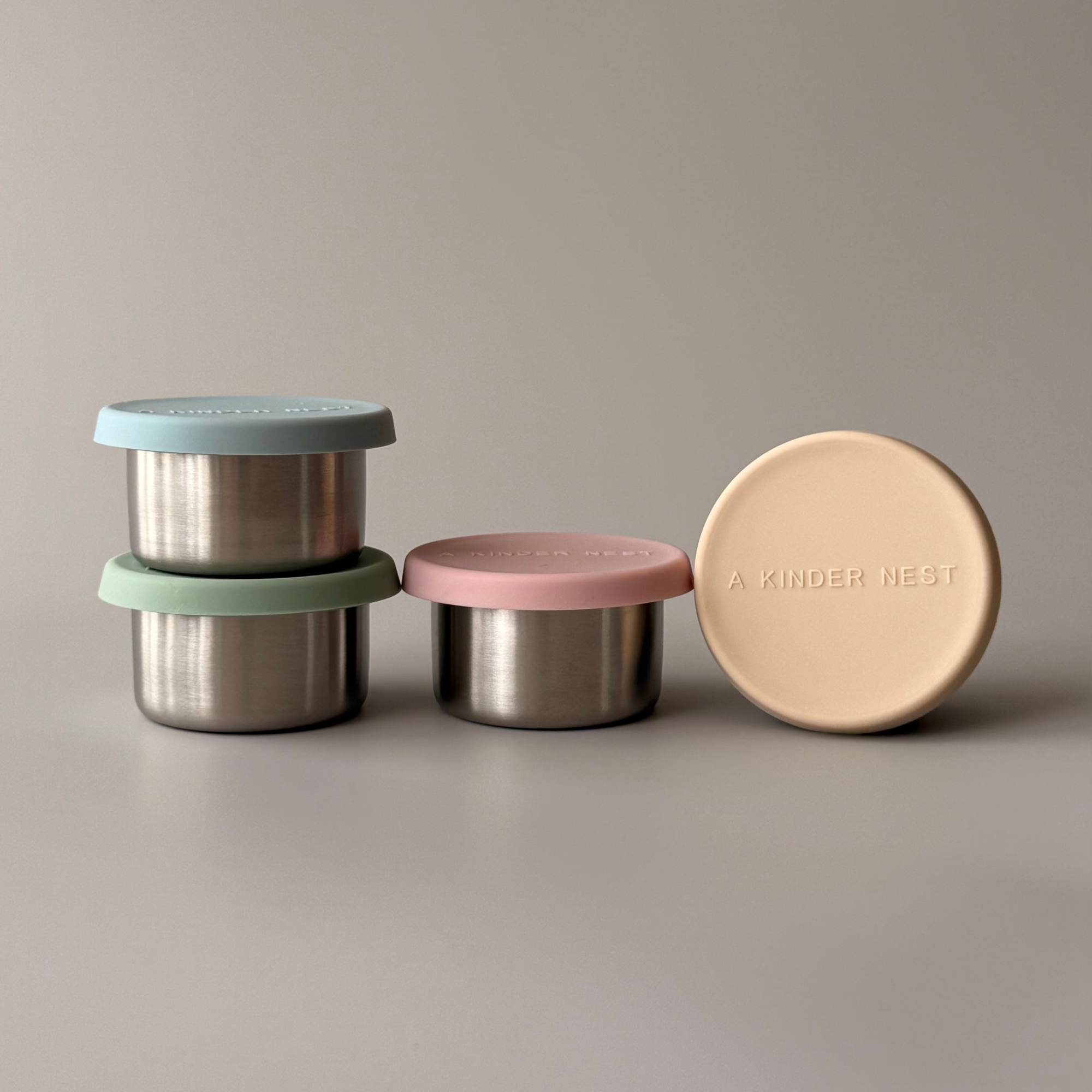 Pair of small metal condiment pots with colorful LFGB-certified silicone lids for plastic-free snacks.